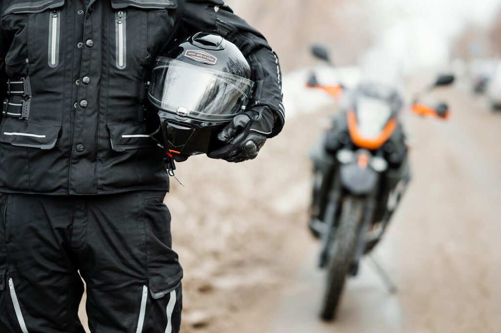 Motociclista segurando capacete em frente a sua moto