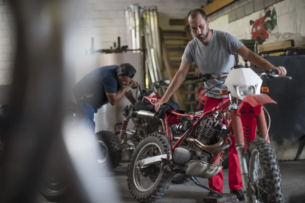 Dois mecânicos realizando revisão da moto desmontada em sua oficina